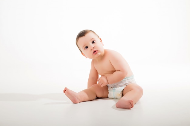 Photo healthy baby boy 9 months old sitting on a white wall isolate, space for text