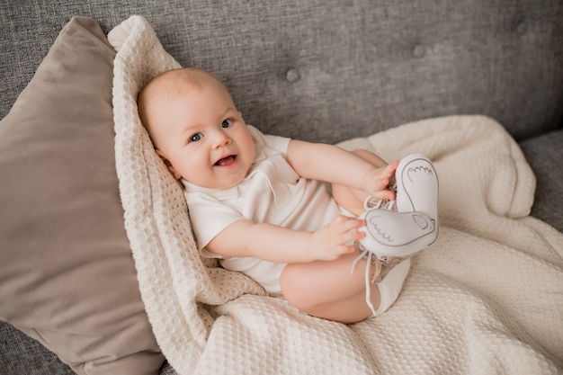 Healthy baby boy lies on the sofa with a soft plaid. Baby's comfort at home