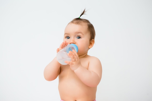 Healthy baby girl smiles and holds a water bottle