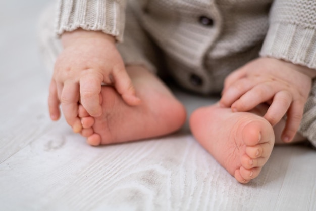 Healthy baby legs feet and toes closeup in a bed knitted suit