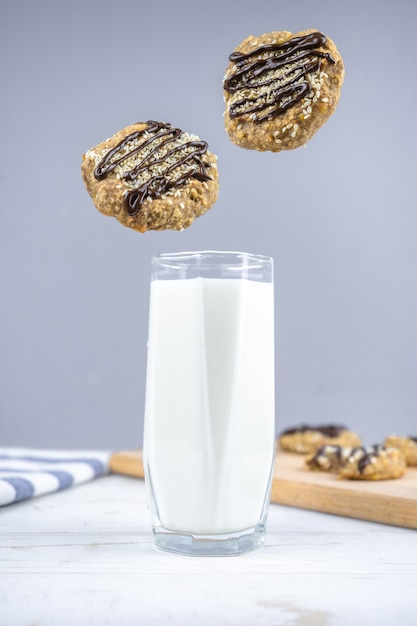 Healthy banana oatmeal cookies with chocolate levitation under\
the glass of milk