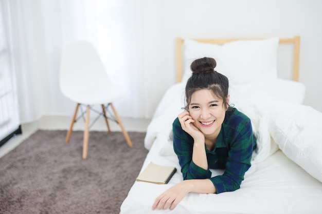 Healthy Beautiful Asian woman smile on bed. Young cute lady lying in bedroom