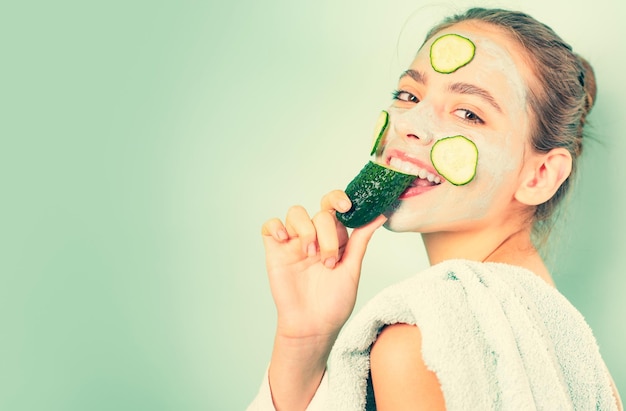 Healthy and beautiful Girl chilling making clay facial mask with cucumber Skin health Woman adorable smiling girl with clay mask Cleaning and care for young skin Proper approach to clean skin