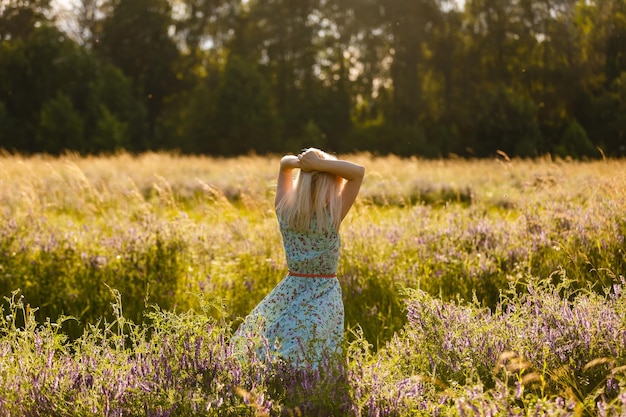 Bella donna sana che cammina all'aperto. giovane donna seducente nel campo di grano, donna sensuale delicata sulla natura. pelle perfetta, capelli ricci.