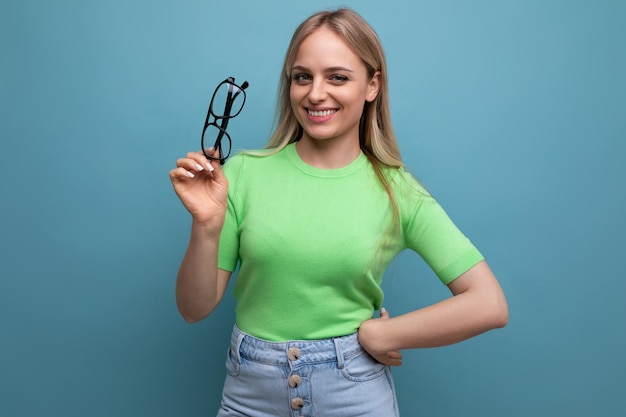 Healthy blond woman holding eyeglasses on blue background