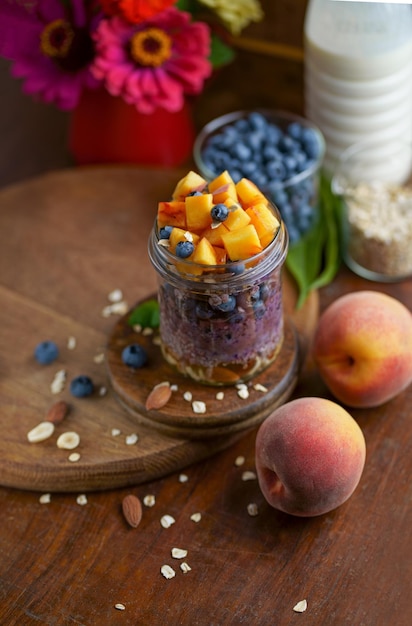 Healthy blueberries and raspberries parfait in mason jars scene on dark rustic background