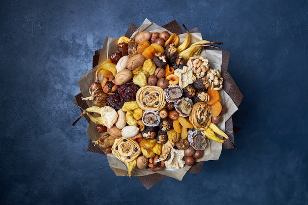 Healthy bouquet of dried fruits and nuts, top view on dark blue