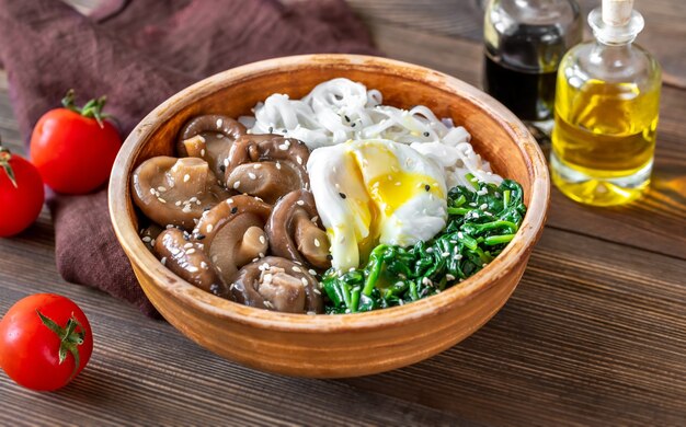 Healthy bowl with rice noodles, marinated shiitake, poached egg and steamed spinach