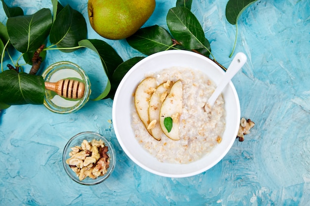 Фото Здоровый завтрак. шар каши с кусками груш и грецких орехов на голубой предпосылке. квартира лежала. копировать пространство вид сверху.