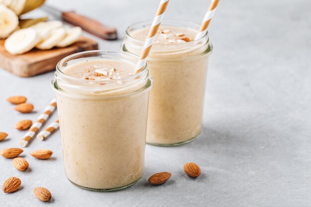 Foto colazione sana frullato di mandorle e banana con cannella e fiocchi d'avena e latte di cocco in vasetti di vetro