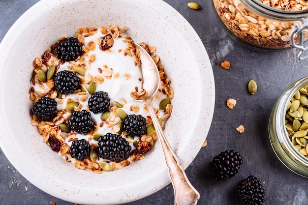 Ciotola sana colazione di yogurt greco con semi di lino muesli semi di zucca e more fresche