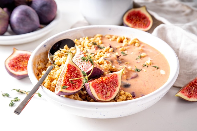 Healthy breakfast bowl with granola fig fruit smoothie or yogurt and fresh figs on white kitchen table copy space Autumn warming snack recipe copy space