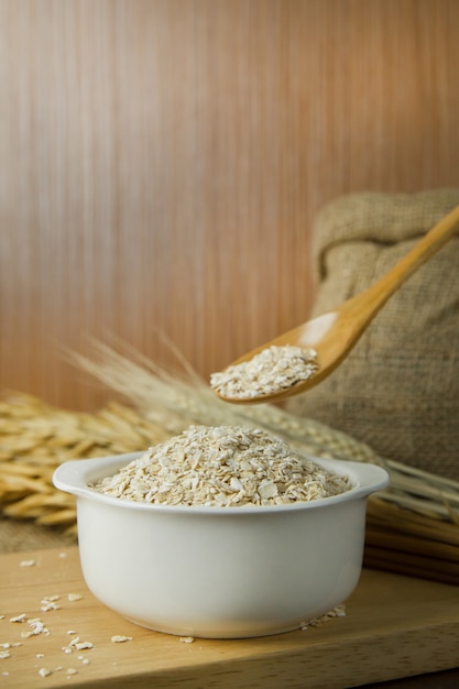 The Healthy breakfast cereal oat flakes in bowl on wooden table