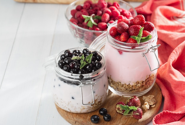 Healthy breakfast cereal with homemade strawberry and blueberry in glass jar on wooden board in home kitchen