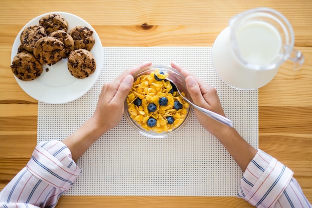 ミルククッキーとブルーベリーとコーンフレークを備えたテーブルの健康的な朝食コンセプトトップビュー