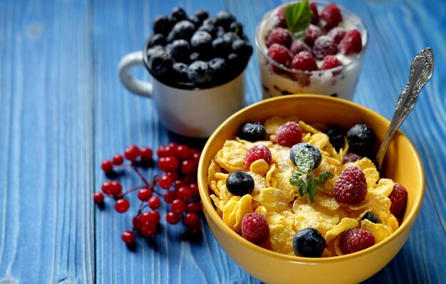 Healthy breakfast corn flakes with raspberries and blueberries and granola with yogurt and berries