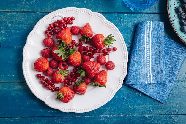 Prima colazione sana che mangia un mix di frutti di bosco rossi freschi