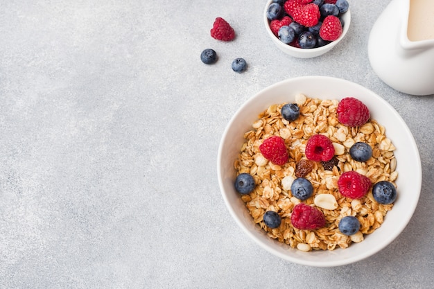 Healthy breakfast. fresh granola, muesli with yogurt and berries on grey background.