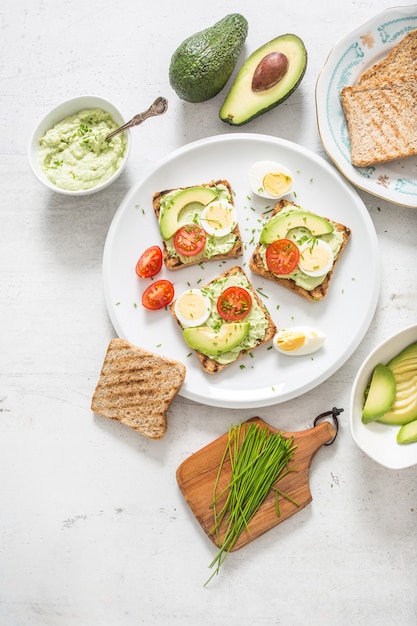 Healthy breakfast from toasts with avocado spread guacamole egg tomato and chives.