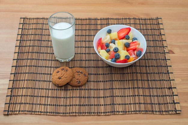 Healthy breakfast of fruit berries and oatmeal cookies with milk on a wooden background