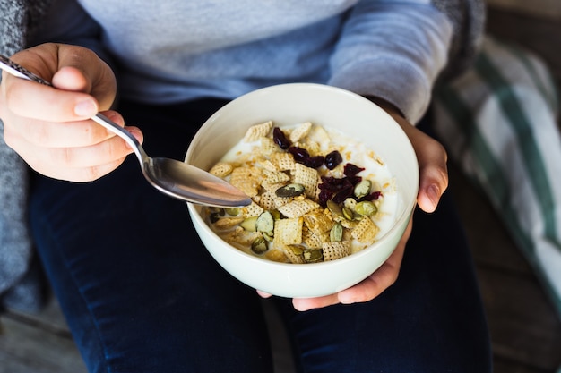 Healthy breakfast. The girl eats fresh granola, muesli with milk berries nuts. View from above.