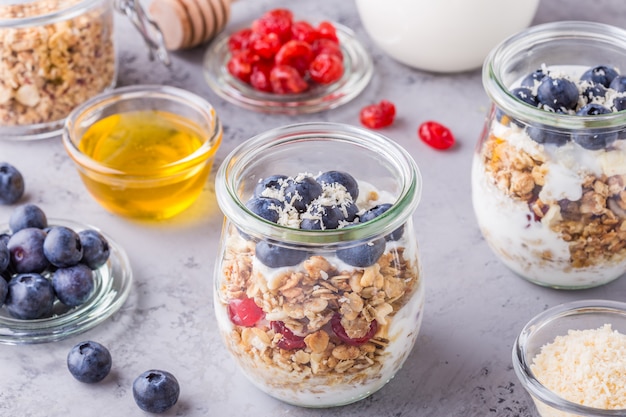 Healthy breakfast - glass jars of oat flakes with fresh fruit, yogurt and honey