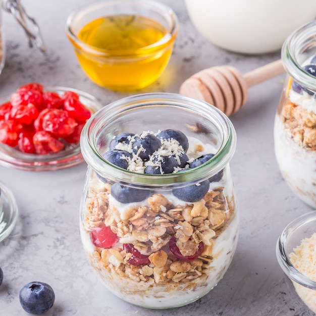 Здоровый завтрак - стеклянные банки из овсяных хлопьев со свежими фруктами, йогуртом и медом.
