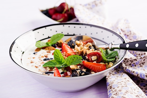 Sana colazione - muesli, fragole, ciliegia, bacche di caprifoglio, noci e yogurt in una ciotola