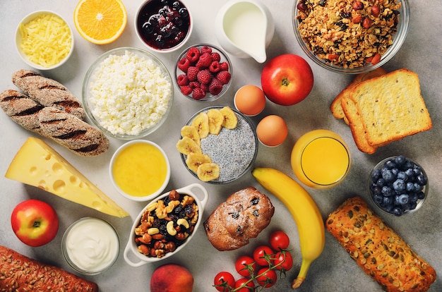 Ingredienti sana colazione, cornice di cibo. muesli, uova, noci, frutta, bacche, pane tostato, latte, yogurt, succo d'arancia, formaggio, banana, mela