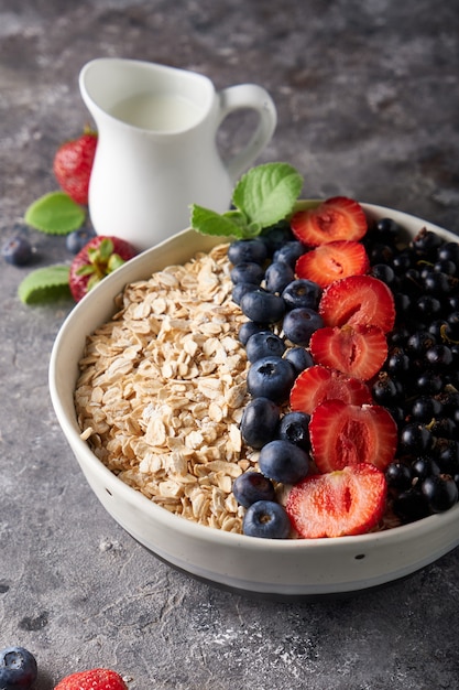 Healthy breakfast, muesli with currants, blueberries and strawberries in bawl on dark space