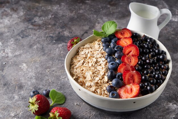 Healthy breakfast, muesli with currants, blueberries and strawberries in bawl on dark space