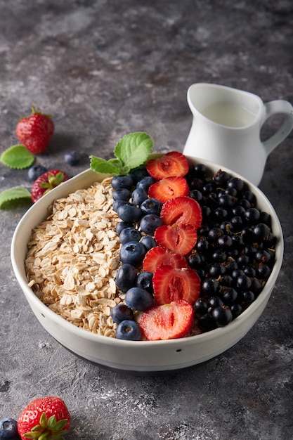 Healthy breakfast, muesli with currants, blueberries and strawberries in bawl on dark space