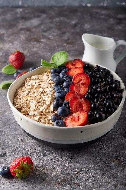 Healthy breakfast, muesli with currants, blueberries and strawberries in bawl on dark space