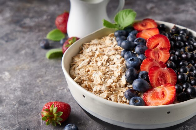 Healthy breakfast, muesli with currants, blueberries and strawberries in bawl on dark space