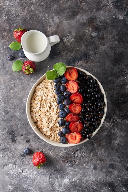 Healthy breakfast, muesli with currants, blueberries and strawberries in bawl on dark space