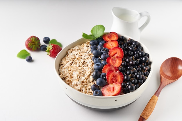 Healthy breakfast, muesli with currants, blueberries and strawberries served in bawl on light space