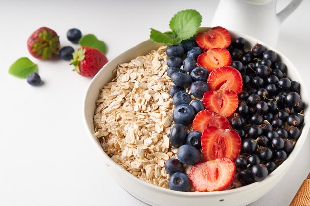 Healthy breakfast, muesli with currants, blueberries and strawberries served in bawl on light space