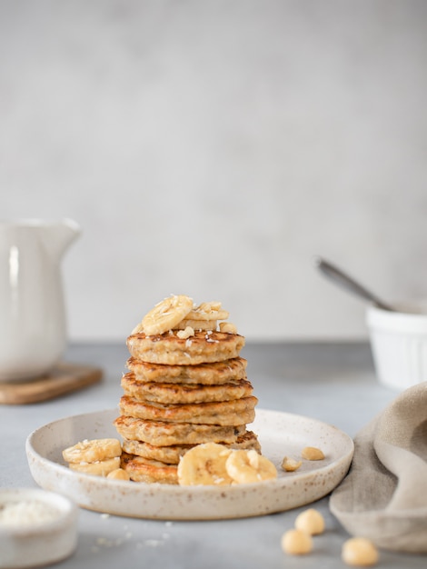 Healthy breakfast, oat pancakes with banana and nuts gray surface,
