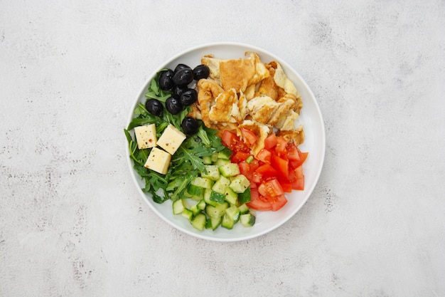 Healthy breakfast. Omelette with fresh mixed vegetables salad rocket, tomatoes, cucumber, olives, cheese. Top view.