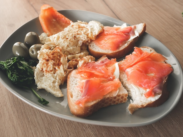 Photo healthy breakfast. omelette with olives, pepper and arugula salad. salmon with wholemeal bread.