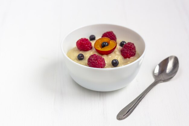 Healthy breakfast porridge for kids. Bowl of baby food on white wooden