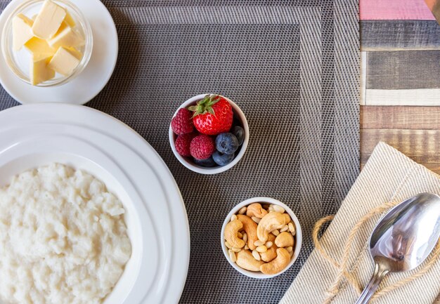 Photo healthy breakfast. rice porridge bowl with berries and nuts on the table, hot and healthy breakfast food, top view