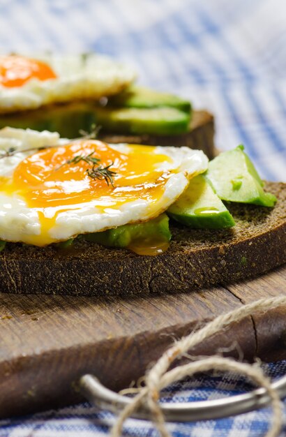 Здоровый завтрак. Бутерброд с ржаным хлебом, авокадо и яичницей