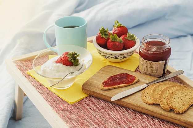 Healthy breakfast served in bed tray with fruit yogurt juice\
and coffee to eat between the blankets healthy lifestyle\
concept