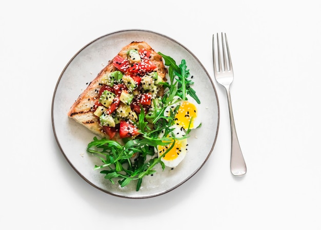 Healthy breakfast snack avocado tomatoes bruschetta boiled egg and arugula on a light background top view