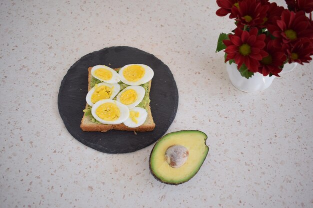 Foto pane tostato sano per la colazione con uova, avocado ed erbe aromatiche