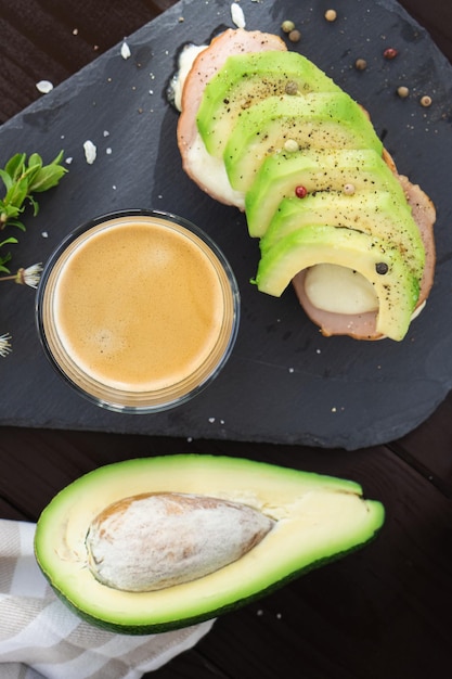 Healthy breakfast Toasted grain bread with fresh sliced avocado ham cheese and cup of coffee