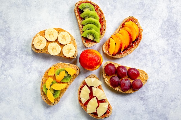 Sana colazione toast con burro di arachidi marmellata di fragole banana uva pesca kiwi ananas noci copia spazio