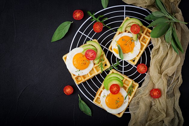 Photo healthy breakfast - waffles, eggs, avocado, tomatoes and herbs. flat lay. top view