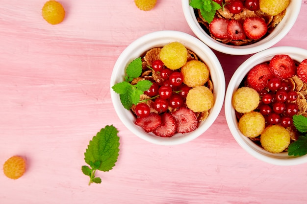 Healthy breakfast on white bowls. Fresh granola, muesli or cereal with berries